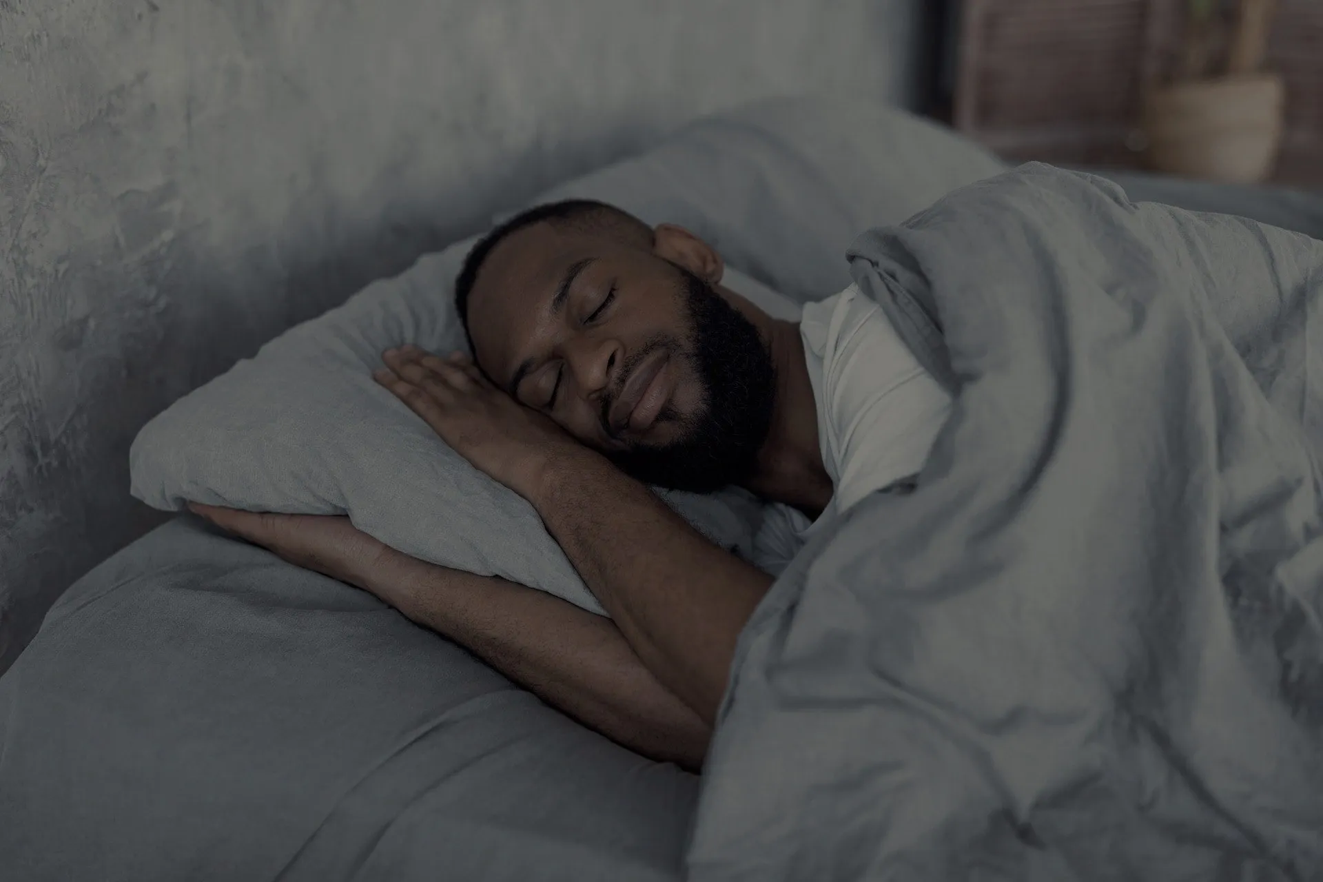 A man sleeps soundly on his side, one hand under the pillow